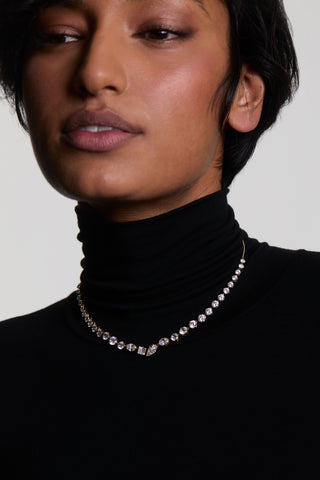 CLOSE UP OF A MODEL WITH SHORT HAIR WEARING THE LUCIA FRONTAL V NECKLACE, STYLED WITH A BLACK TURTLENECK
