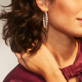CLOSE UP IMAGE OF A MODEL WEARING THE LEAH STATEMENT HOOP EARRINGS AND A BURGUNDY SILK TOP.