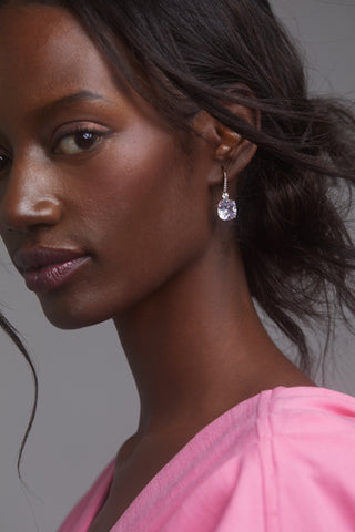 MACARON CZ DROP EARRINGS ON MODEL. IT IS A CLOSE UP SHOT WITH HER FACING THE CAMERA. HER HAIR IS IN A LOOSE BUN AND SHE IS WEARRING A PINK DRESS. 