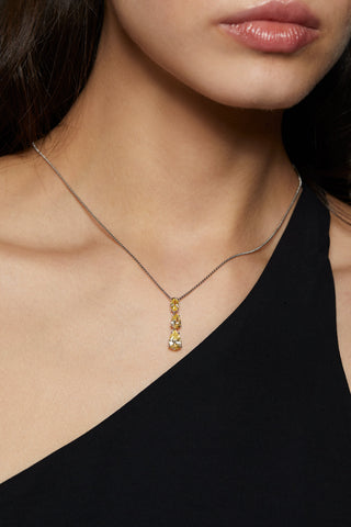 IMAGE OF MODEL WEARING NATURAL BEAUTY YELLOW SHORT Y NECKLACE. IT IS A TIGHT CROP OF HER NECKLINE. SHE IS WEARING AN OFF THE SHOULDER BLACK TOP. 